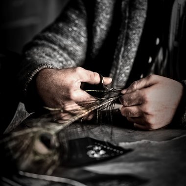 Mit dem „Faden“ aus der Feder des Pfaus wird gestickt.