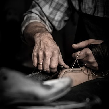 Mit der Ahle zieht der Schuster den Zwirn durch die Löcher.